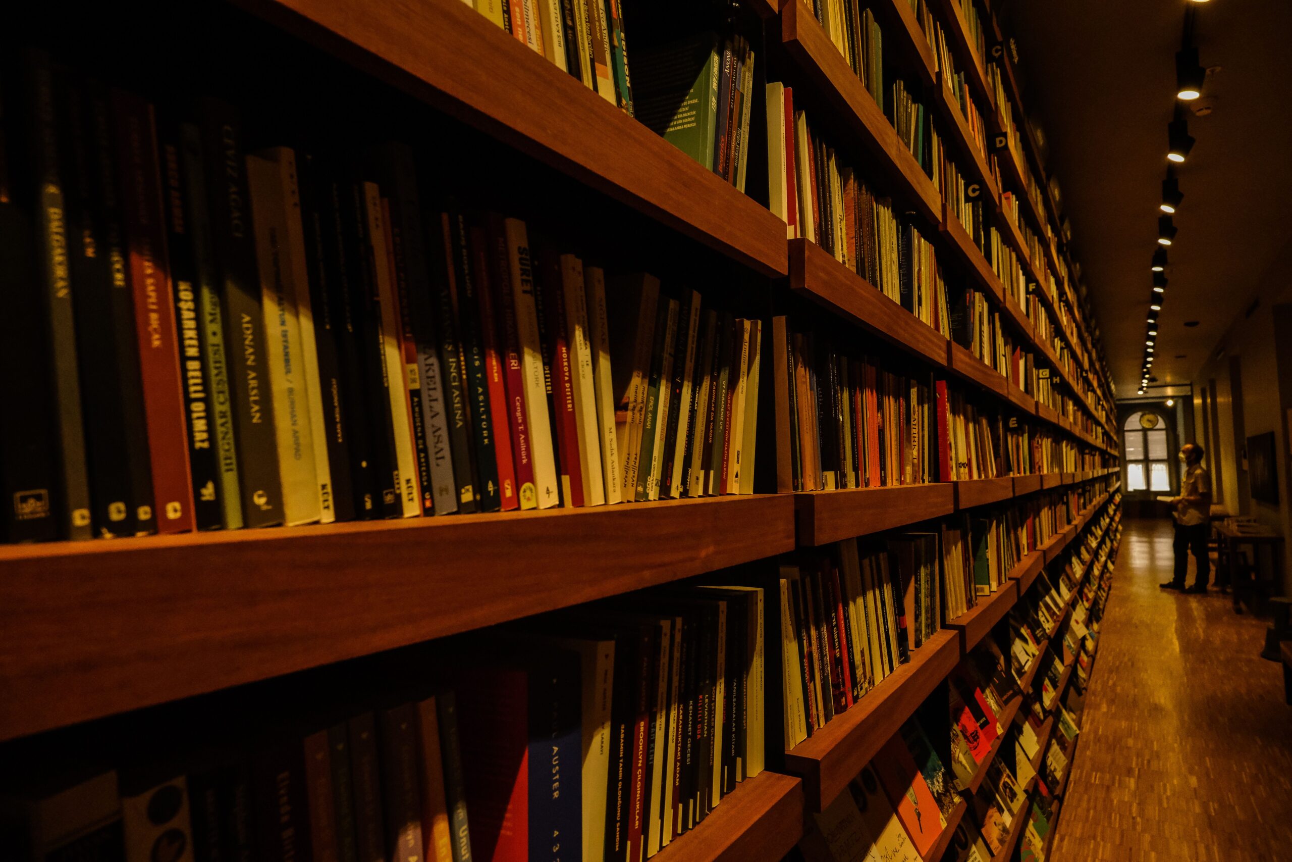 Long shelves filled with books in a warmly lit library interior, ideal for reading enthusiasts.
